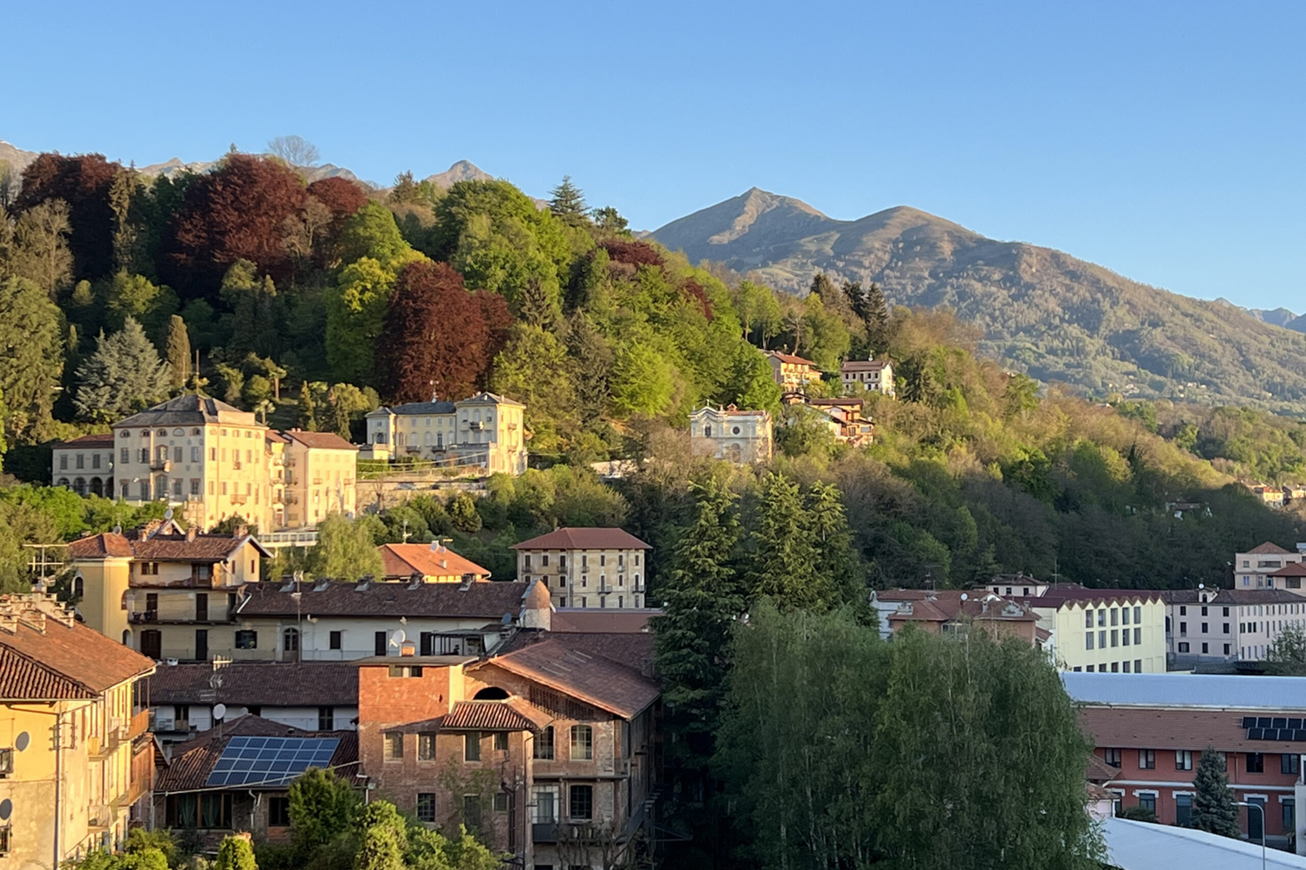 Golden autumn light shines on the rooftops and changing foliage of Biella