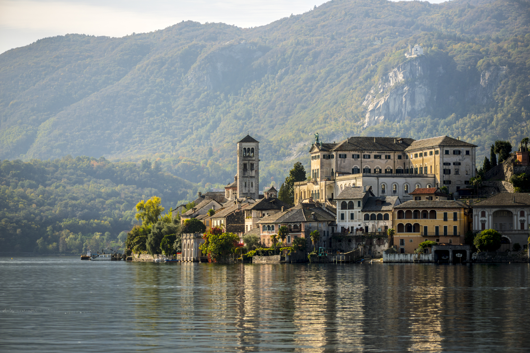 In the midground, a town perches next to a lake (foreground), with mountains behind and reflections in the water.